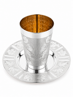 A silver Kiddush cup with an ornate floral engraving pattern, shown on a matching silver Kiddush plate by hadad bros silverware