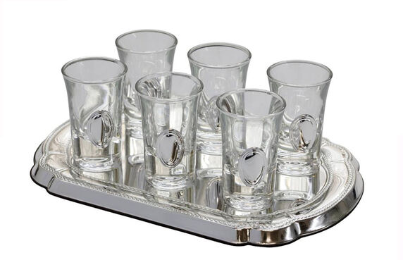 Set of six clear shot glasses on a silver tray with a white background