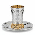Silver and gold kiddush cup with ornate design on a white background