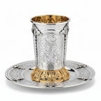 Silver and gold kiddush cup with ornate design on a white background