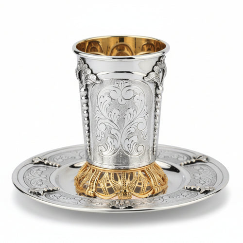 Silver and gold kiddush cup with ornate design on a white background