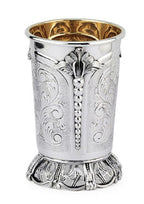 Silver kiddush cup with gold interior on a matching tray against a white background