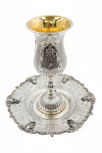 Silver kiddush goblet with gold interior on a matching silver tray against a white background