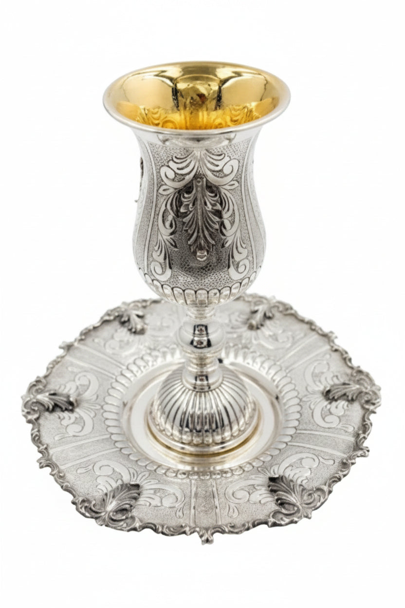 Silver kiddush goblet with gold interior on a matching silver tray against a white background