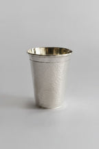 Metallic silver cup with hammered texture on a white background