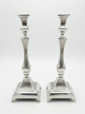 Pair of silver candlesticks with intricate designs on a white background