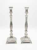 Pair of silver candlesticks with intricate designs on a white background by hadad bros