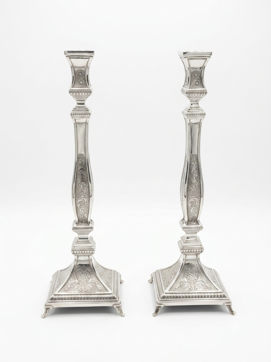 Pair of silver candlesticks with intricate designs on a white background by hadad bros
