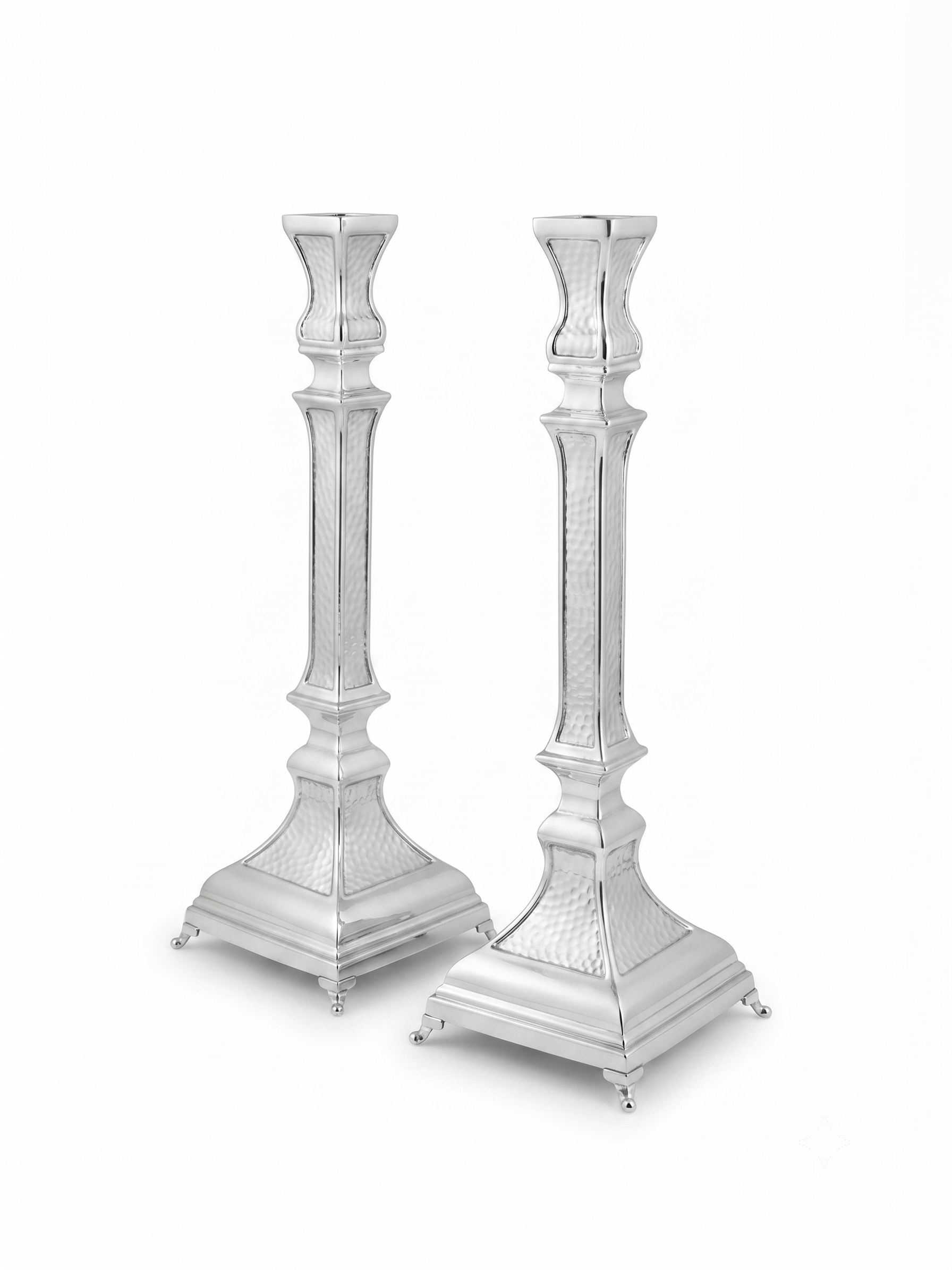A pair of ornate silver candlesticks with detailed textured engravings and flared bases, shown against a plain white background. hammered silver candlesticks by hadad bros silverware