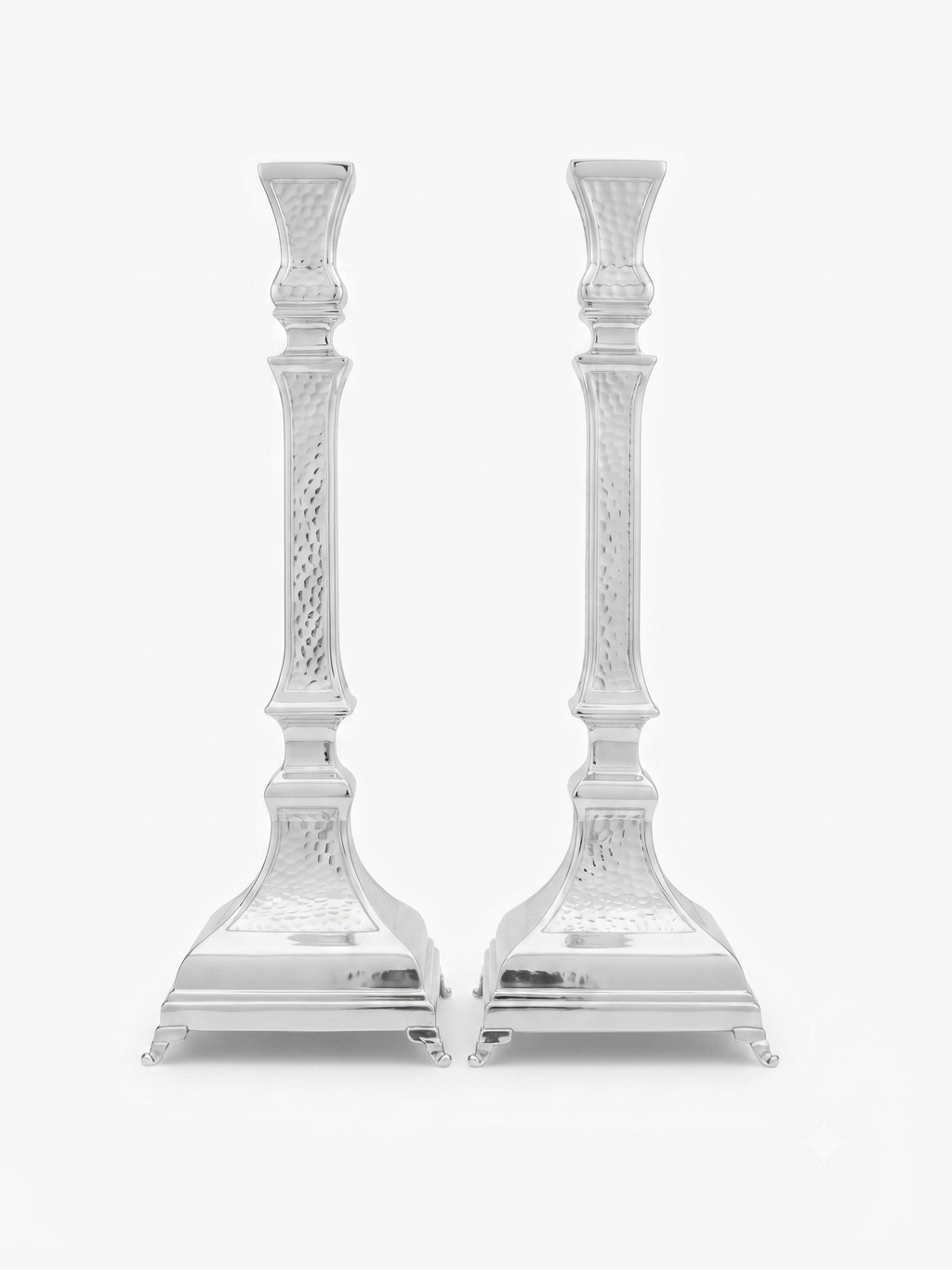A pair of ornate silver candlesticks with detailed textured engravings and flared bases, shown against a plain white background. hammered silver candlesticks by hadad bros silverware