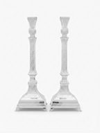 A pair of ornate silver candlesticks with detailed textured engravings and flared bases, shown against a plain white background. hammered silver candlesticks by hadad bros silverware