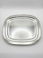 Silver platter with decorative edge on a light gray background