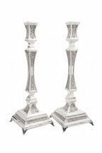 Two silver candlesticks with intricate designs on a white background