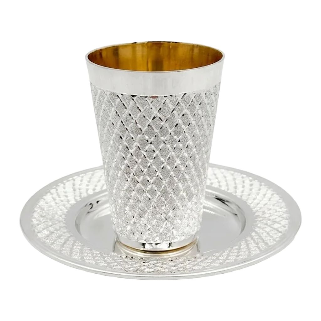 Silver kiddush cup with gold interior and diamonds pattern on a matching tray against a white background