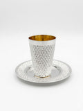 Silver kiddush cup with gold interior and diamonds pattern on a matching tray against a white background