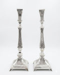 Pair of silver candlesticks with intricate designs on a white background