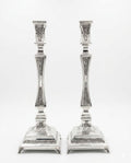 pair of Silver candlesticks with intricate designs on a white background