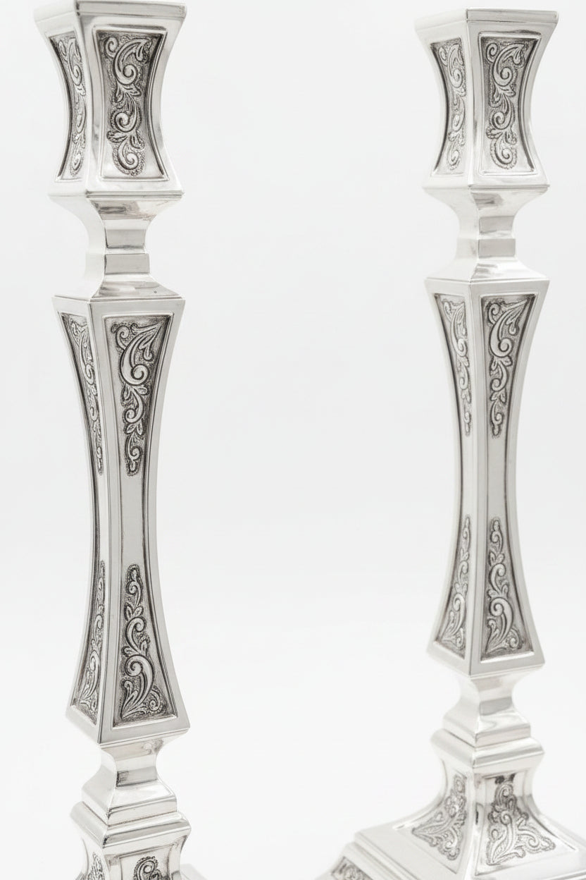 pair of Silver candlesticks with intricate designs on a white background