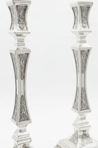 pair of Silver candlesticks with intricate designs on a white background