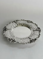 Silver kiddush cup with intricate designs on a matching saucer against a white background