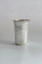 Metallic silver cup with hammered texture on a white background