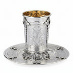 Silver kiddush cup with gold interior on a matching tray against a white background