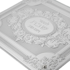 Decorative silver challah tray with intricate designs and Hebrew text on a white background