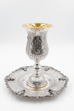 Silver kiddush goblet with gold interior on a matching silver tray against a white background
