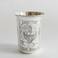 Silver cup with intricate black floral patterns on a white background